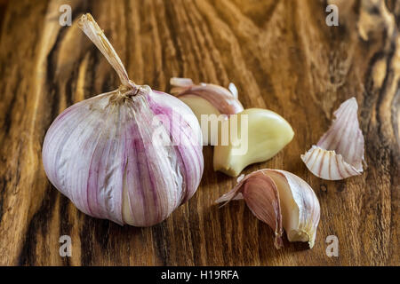 Garlic on Wooden Vintage Background. Fresh Garlic Bulb with Garlic Cloves on Chopping Board. Stock Photo