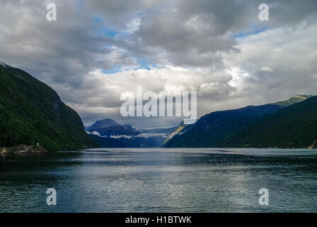 Cloudy sky over banks of fjord. Mountains with green forest, Eidfjord, Norway Stock Photo