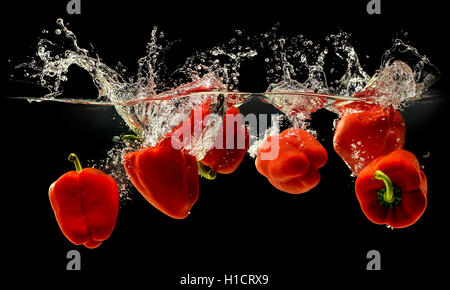 Group of bell pepper falling in water on black Stock Photo