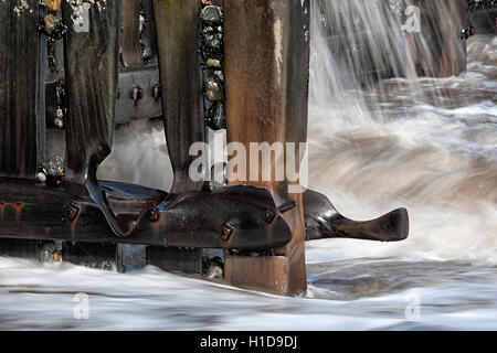 Sea water breaking through groynes on beach in slow motion Stock Photo