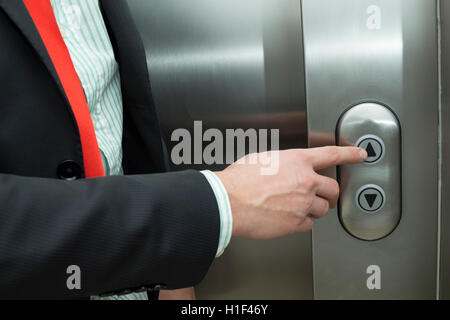 Businessman pressing elevator up button Stock Photo