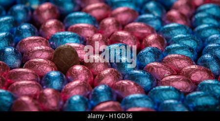 One unwrapped chocolate egg, surrounded by foil wrapped eggs Stock Photo