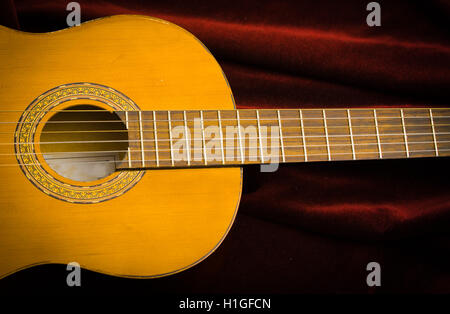 Classical nylon guitar lying on red velvet textile, artistic instrument presentation Stock Photo