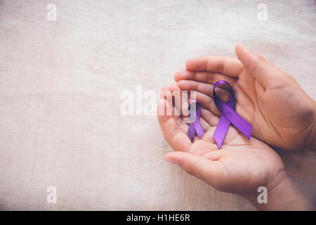 Hands holding Purple ribbons, toning copy space background, Alzheimer's disease, Pancreatic cancer, Epilepsy awareness, Hodgkin Stock Photo