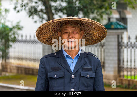 Portrait of unidentified Chinese guard in traditional straw wide-brimmed hat under the rain Stock Photo