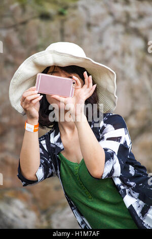 Japanese woman tourist photographing a bird at the KL Bird Park in Kuala Lumpur, Malaysia using her smartphone. Stock Photo