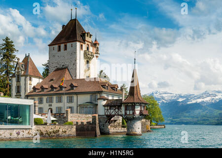 Beautiful little tower of Oberhofen castle in the Thun lake with mountains on background in Switzerland, near Bern. Stock Photo