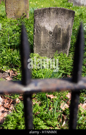 Old gravestones, weather worn in an overgrown graveyard. Stock Photo