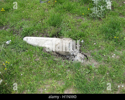 Broken concrete column. Destroyed a concrete fence on the grass. Stock Photo