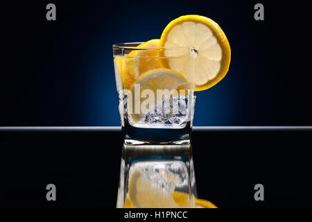 Glass of alcoholic drink with lemon on a reflective background Stock Photo