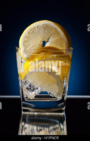 Glass of alcoholic drink with lemon on a reflective background Stock Photo