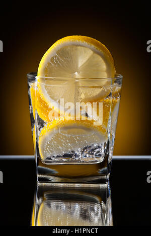 Glass of alcoholic drink with lemon on a reflective background Stock Photo