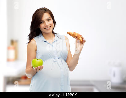 happy pregnant woman with apple and croissant Stock Photo