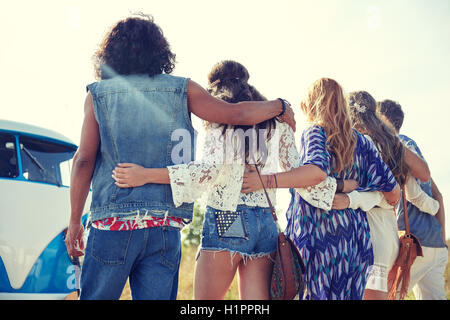 young hippie friends hugging over minivan car Stock Photo