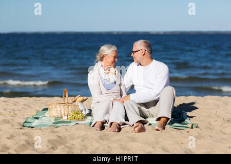 happy senior couple having picnic on summer beach Stock Photo