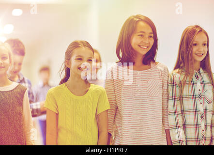 group of smiling school kids walking in corridor Stock Photo