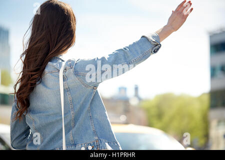 young woman or girl catching taxi on city street Stock Photo