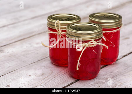 Bottles with homemade red juice and jars of various pickled