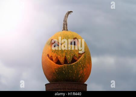 pumpkin head with a fire in the middle against the background of the cloudy sky Stock Photo