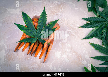 Wooden hands holding a single marijuana leaf over white wood background Stock Photo
