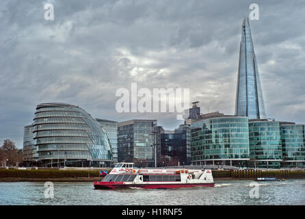 Tourist boat on river Thames with London mayor's office and The Shard in background Stock Photo