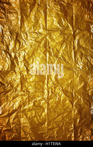 Shining background of old wrinkled and folded yellow wrapping paper Stock Photo