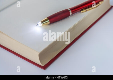 LED Light Ballpoint Pen Lying On Open Book Stock Photo