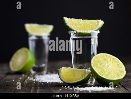 Tequila silver shots with lime slices and salt on grunge wooden board Stock Photo