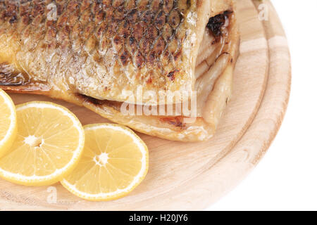 Fried carp on wooden platter with lemon. Stock Photo