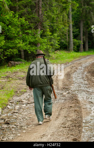 An old hunter walks in Romanian mountains. Stock Photo