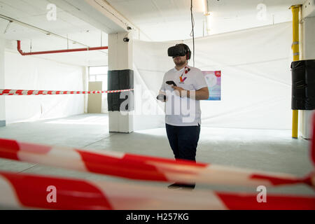 Nuremberg, Germany. 13th Sep, 2016. Aydin Tutkun, programmer at the Nuremberg start-up business 'Virtues', acts in a virtual world while wearing virtual reality glasses, two controllers for the hands and headphones in Nuremberg, Germany, 13 September 2016. The screen on the left shows the picture from his VR glasses. Virtual realities fascinate many people, but not all can afford the expensive equipment. The company 'Virtuis' wants take advantage of this. PHOTO: DANIEL KARMANN/dpa/Alamy Live News Stock Photo