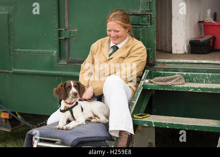 Gransden Cambridgeshire UK, 24th September 2016.  A woman and springer spaniel dog take a break from looking after their Suffolk Punch horses at the Gransden and District Agricultural Society annual show. The show includes traditional rural activities such as produce competitions, flower arranging, heavy horses, vintage farm machinery, pony club competition, foxhounds, livestock and dog show. There are a variety of trade stands, livestock, craft stalls, funfair, and food. Credit:  Julian Eales/Alamy Live News Stock Photo