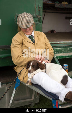 Gransden Cambridgeshire UK, 24th September 2016.  A woman and springer spaniel dog take a break from looking after their Suffolk Punch horses at the Gransden and District Agricultural Society annual show. The show includes traditional rural activities such as produce competitions, flower arranging, heavy horses, vintage farm machinery, pony club competition, foxhounds, livestock and dog show. There are a variety of trade stands, livestock, craft stalls, funfair, and food. Credit:  Julian Eales/Alamy Live News Stock Photo