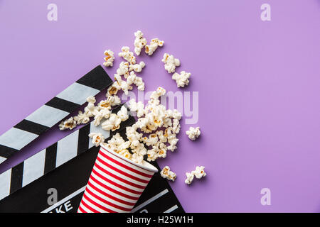 Popcorn and clapperboard on colorful background. Stock Photo