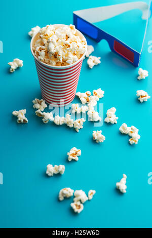 Popcorn and 3D glasses on blue background. Stock Photo