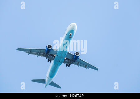 Passenger plane flying in clear blue sky Stock Photo