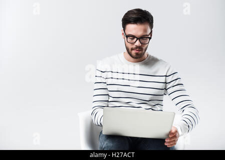 Concentrated bearded man using laptop. Stock Photo