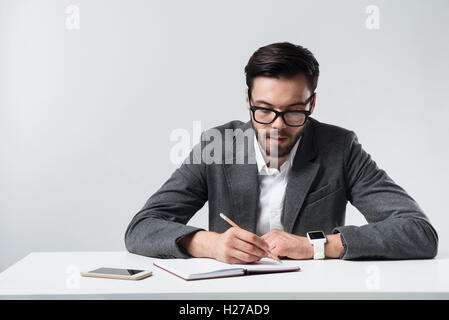 Serious bearded man making notes. Stock Photo