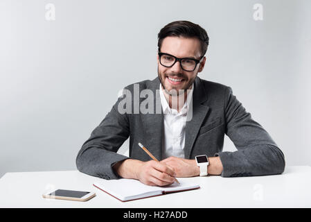 Smiling bearded bespectacled man making notes. Stock Photo