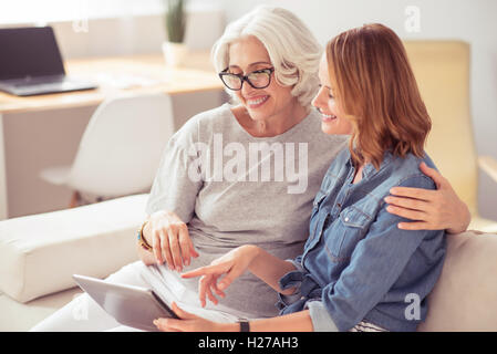 Positive senior woman and her daughter using tablet Stock Photo