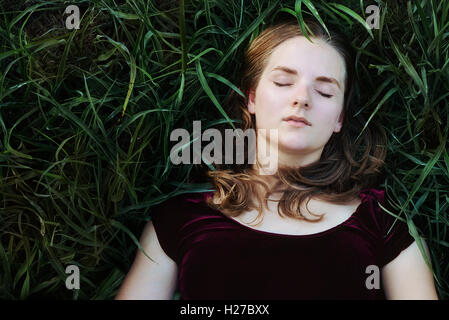 Girl laying in green grass outside Stock Photo