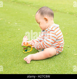 Outdoor portrait of Asian baby boy playing sitting and crawling on the green grass field in the park Stock Photo