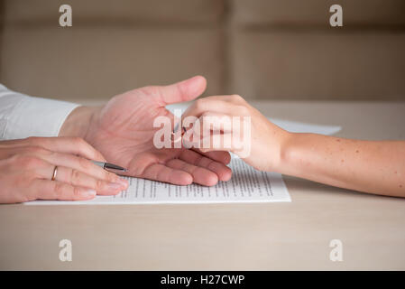 Wife and husband signing divorce documents, woman returning wedding ring Stock Photo