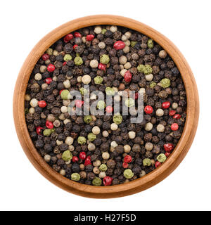 Mixed peppercorns in a wooden bowl on white background. Black, green, white and pink pepper. Dried seeds of Piper nigrum. Stock Photo