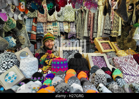 Riga, Latvia - December 25, 2015: Festively dressed smiling man selling woolen clothes at Riga Christmas Market. Warm mittens, gloves, socks and hats are one of the most common goods at the market. Stock Photo