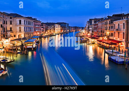 Blue water of Venice Grand Canal from Rialto bridge at sunset when nearby palaces, cafes and services are illuminated. Stock Photo