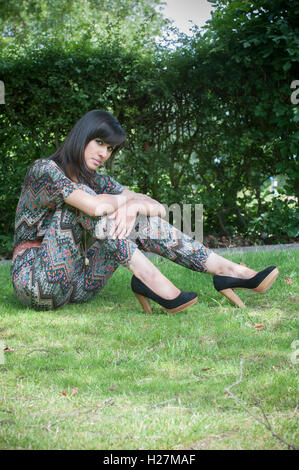 Beautiful Indian woman sat on the grass staring