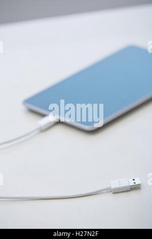Tablet computer with USB cable laying on a table Stock Photo