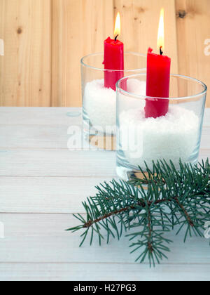 Two red burning candles in the glasses and blue spruce branches on the wooden planks background Stock Photo