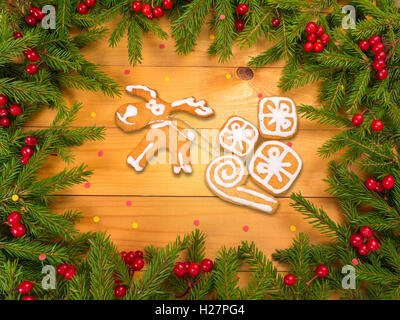 Reindeer with gifts cookies in Christmas tree frame on the wooden planks background sprinkled with red and yellow confetti Stock Photo
